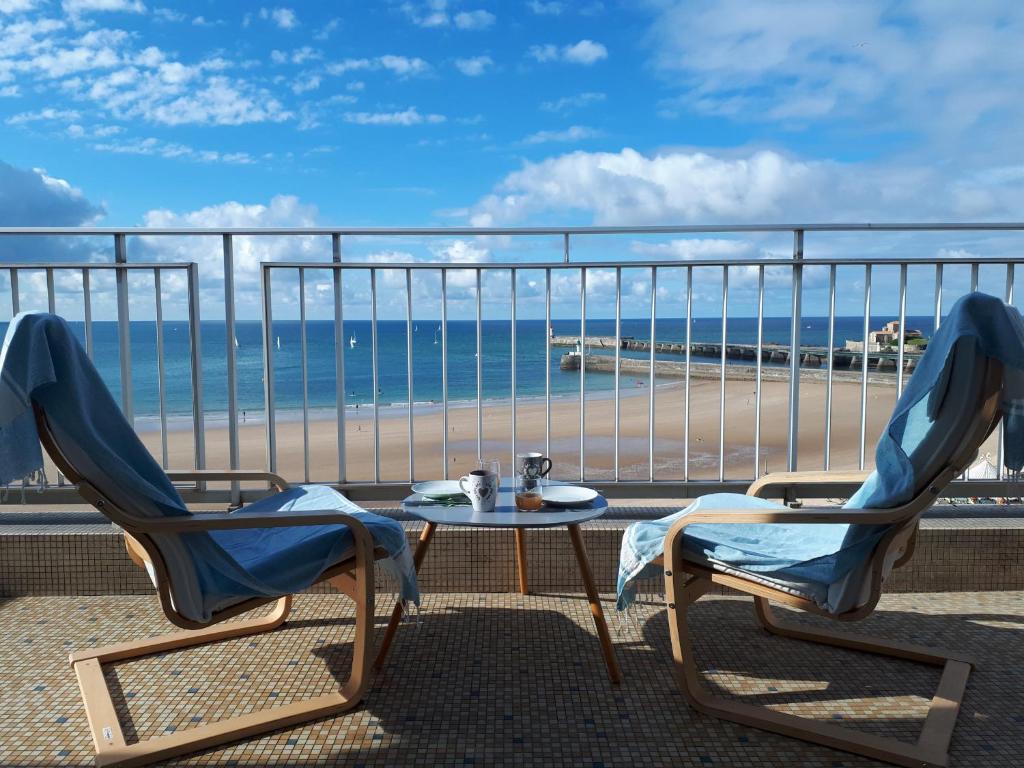 - deux chaises et une table sur un balcon avec une plage dans l'établissement Appartement face mer 1 etoile - WIFI - Le Remblai, à Les Sables-dʼOlonne