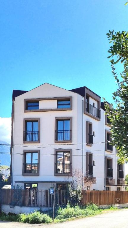 a white building with black windows and a fence at Tivat lovely cosy studio in Tivat