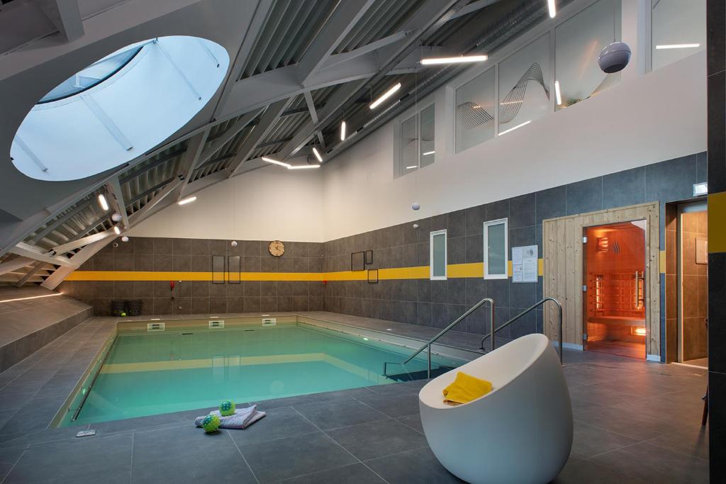 uma piscina com banheira e uma piscina em Domitys l'Esquisse em Valenciennes