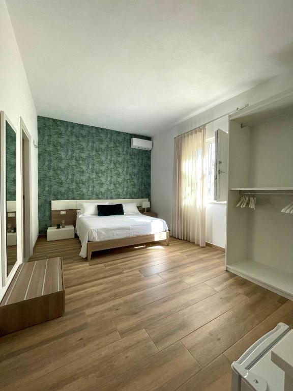 a bedroom with a white bed and a green wall at B&B SoleLuna in Lampedusa