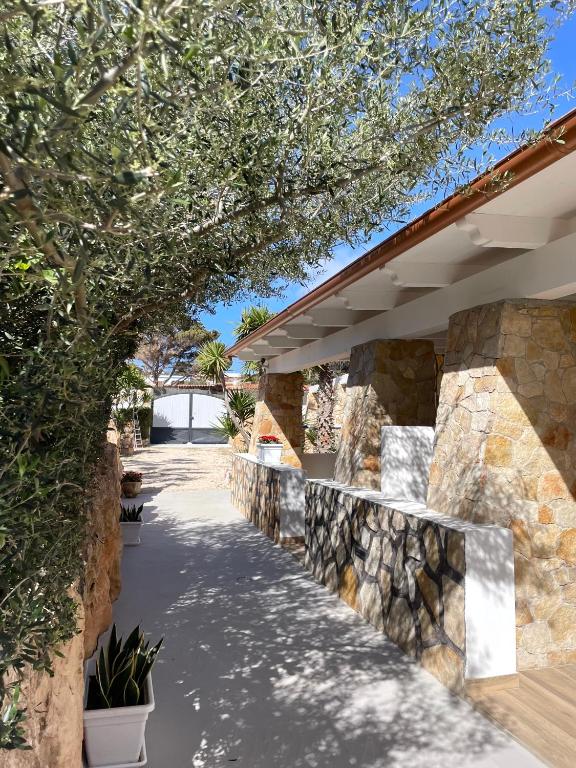 a stone wall next to a walkway with trees at B&B SoleLuna in Lampedusa