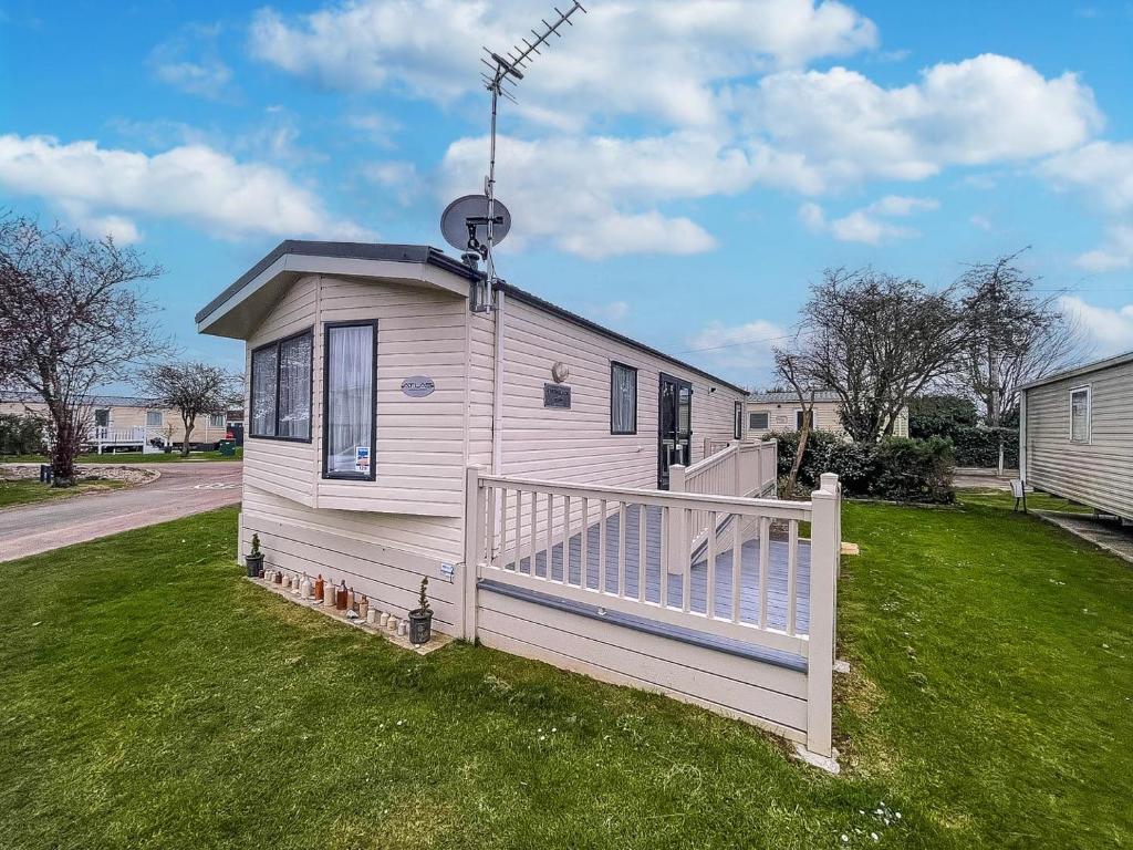 a small white house with a porch on the grass at Great 4 Berth Caravan With Wheelchair Access In Suffolk, Ref 68129bs in Lowestoft