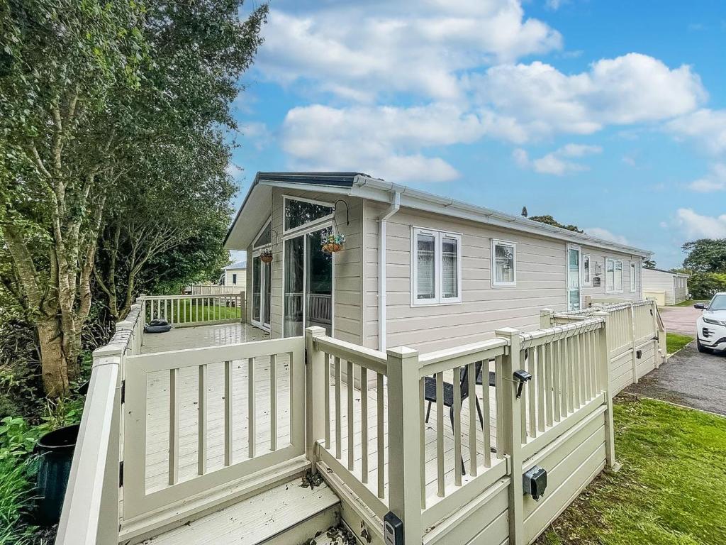 a tiny house with a white fence at Stunning Lodge With Decking At Oaklands Holiday Park In Essex Ref 39017rw in Clacton-on-Sea