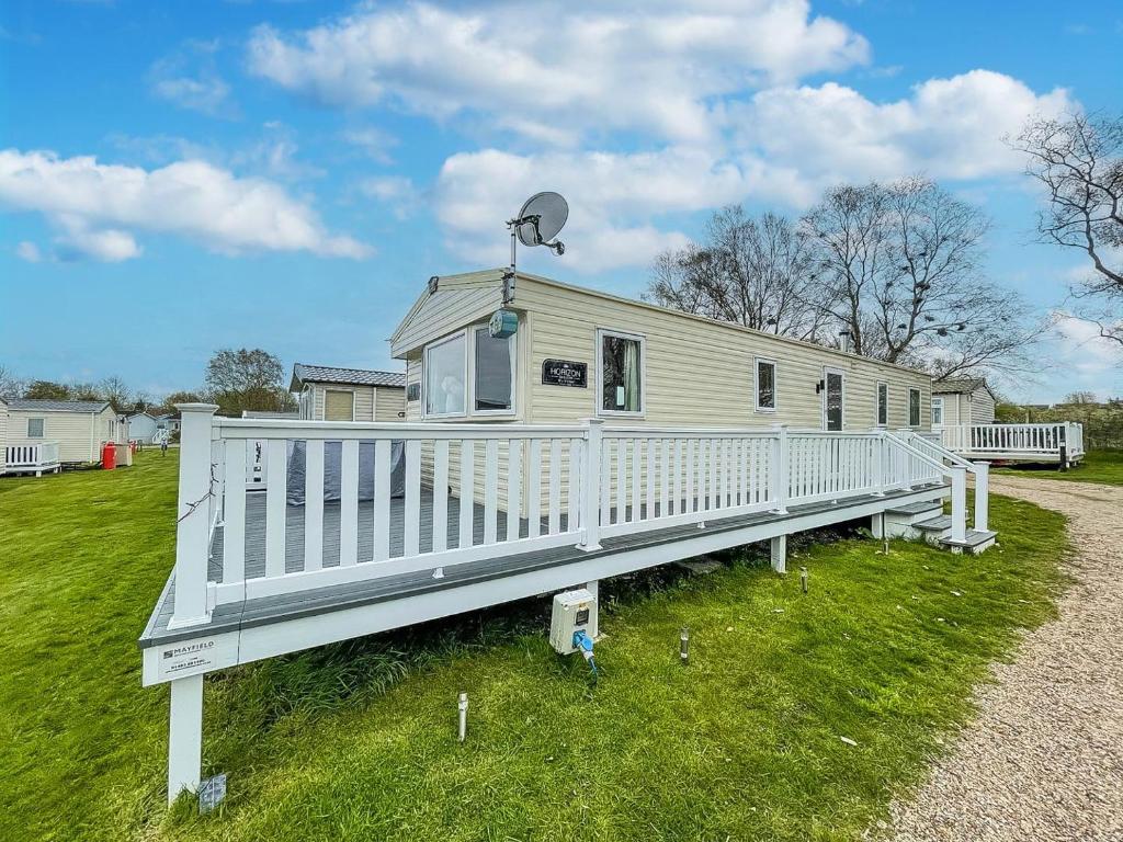 a mobile home with a white porch and a fence at Lovely Caravan With Decking And Free Wifi In Lowestoft Ref 12106b in Lowestoft