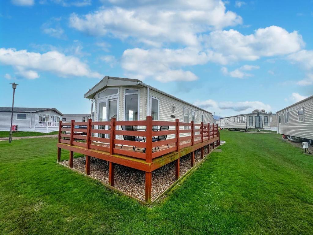 a building with a bench in a grass field at Lovely 6 Berth Caravan With Decking, Wifi And Onsite Beach Access Ref 68004cl in Lowestoft