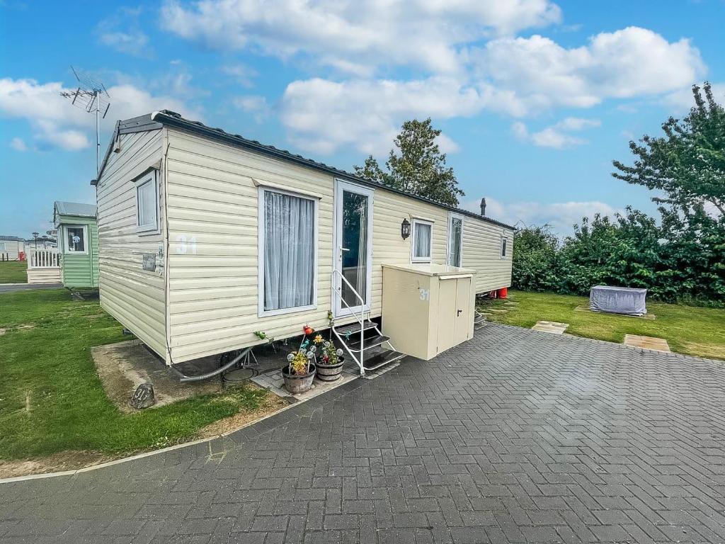 a white tiny house sitting on top of a driveway at Lovely 6 Berth Caravan At Oaklands Holiday Park Ref 39031cw in Clacton-on-Sea