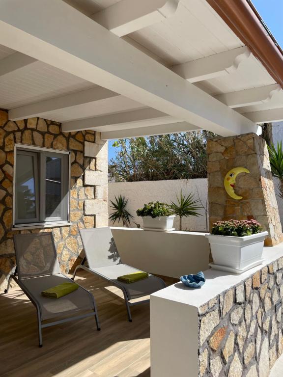 a patio with two chairs and a stone wall at B&B SoleLuna in Lampedusa