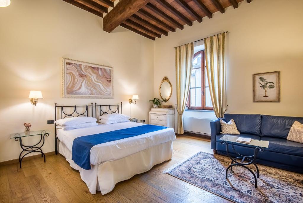 - une chambre avec un lit et un canapé bleu dans l'établissement Hotel Palazzo Squarcialupi, à Castellina in Chianti