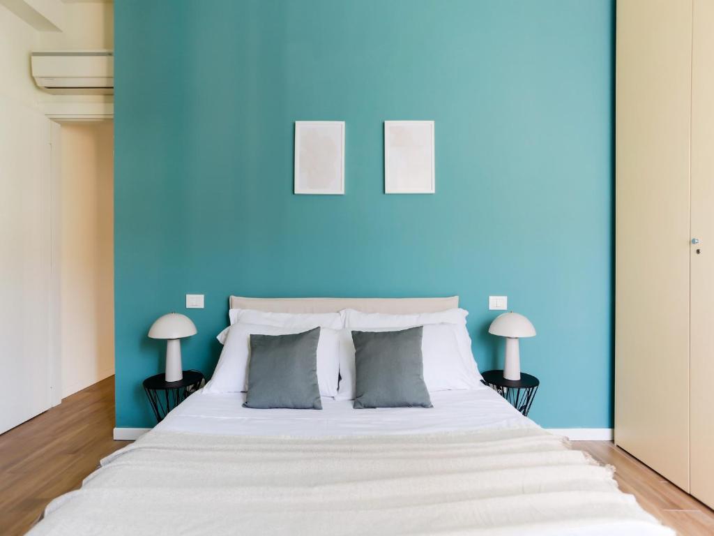 1 dormitorio con 1 cama blanca grande y paredes azules en The Best Rent - Morosini Apartment, en Milán