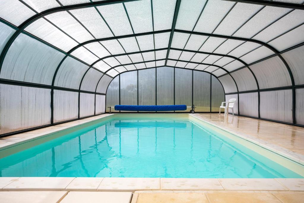 an indoor swimming pool with a glass ceiling at Maison avec piscine 20min plage in Guerlesquin