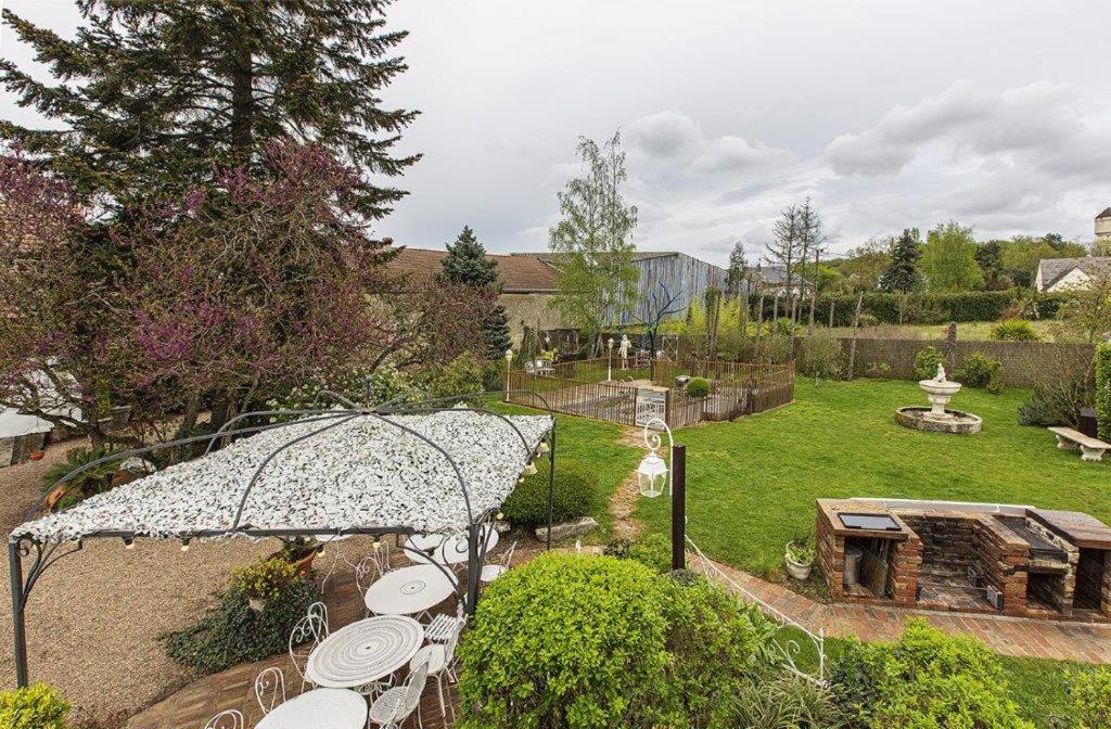een tuin met tafels en een parasol in een tuin bij Gite de la chabardiere in Mont-près-Chambord