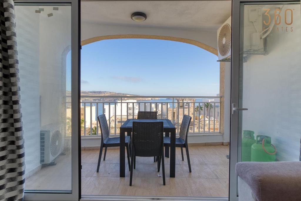 een eetkamer met een tafel en stoelen op een balkon bij Designer home with stunning sea views in St Pauls by 360 Estates in St Paul's Bay
