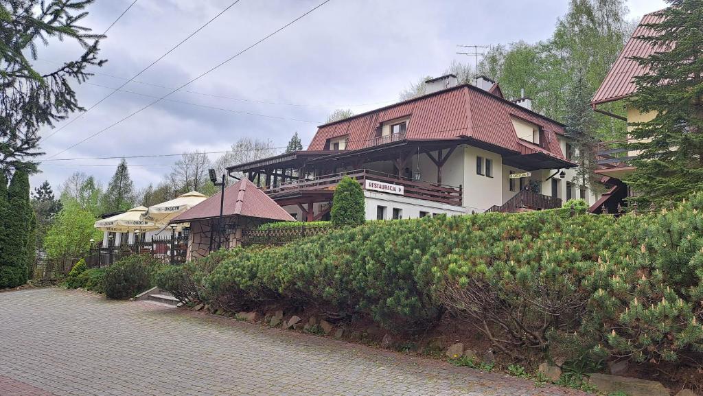 una casa grande con techo rojo en una colina en Zajazd-restauracja Zyga en Iwkowa