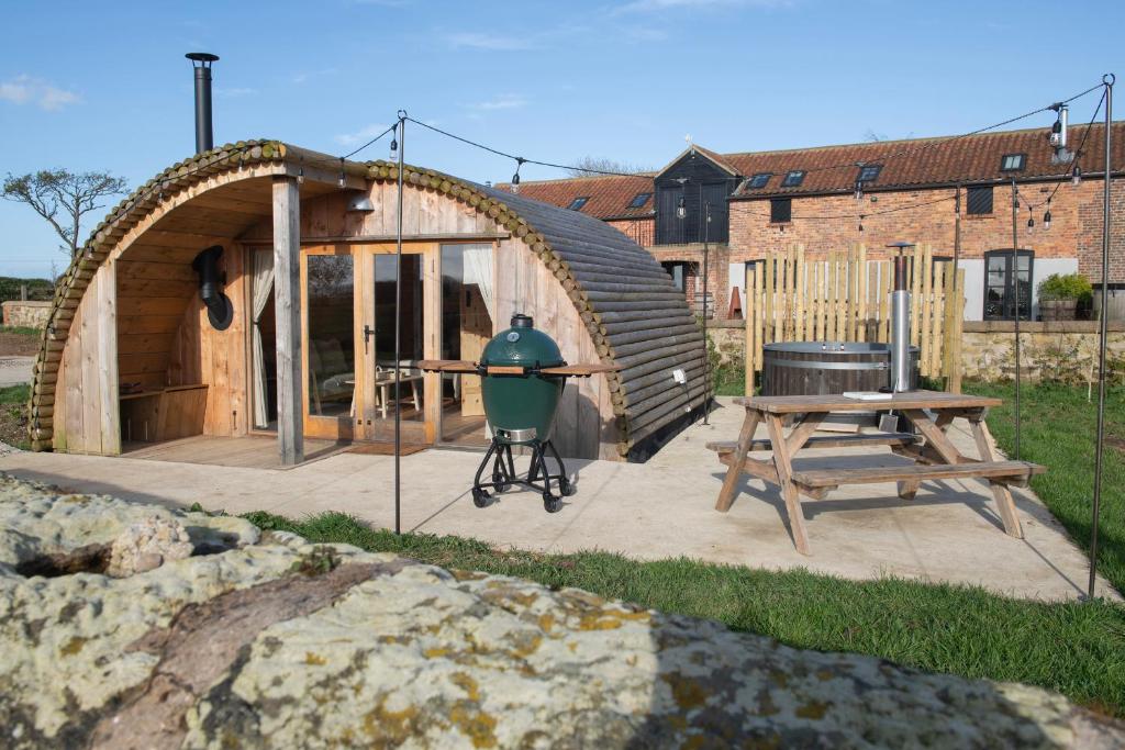 a wooden house with a grill and a picnic table at Glamping Pod 3 Harmony in Scarborough