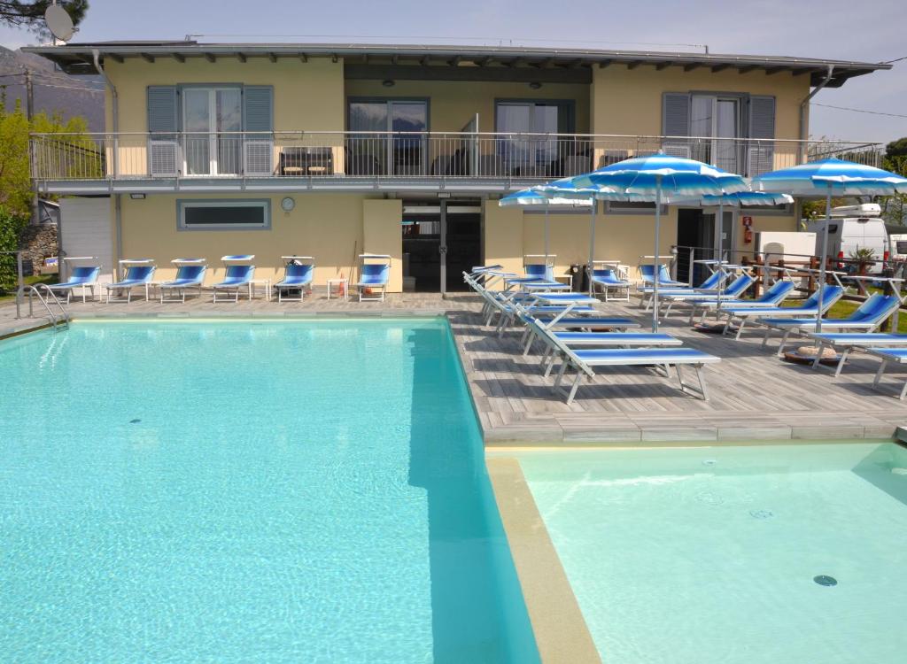 a swimming pool with blue chairs and umbrellas at Apartments Camping Italia' 90 in Domaso