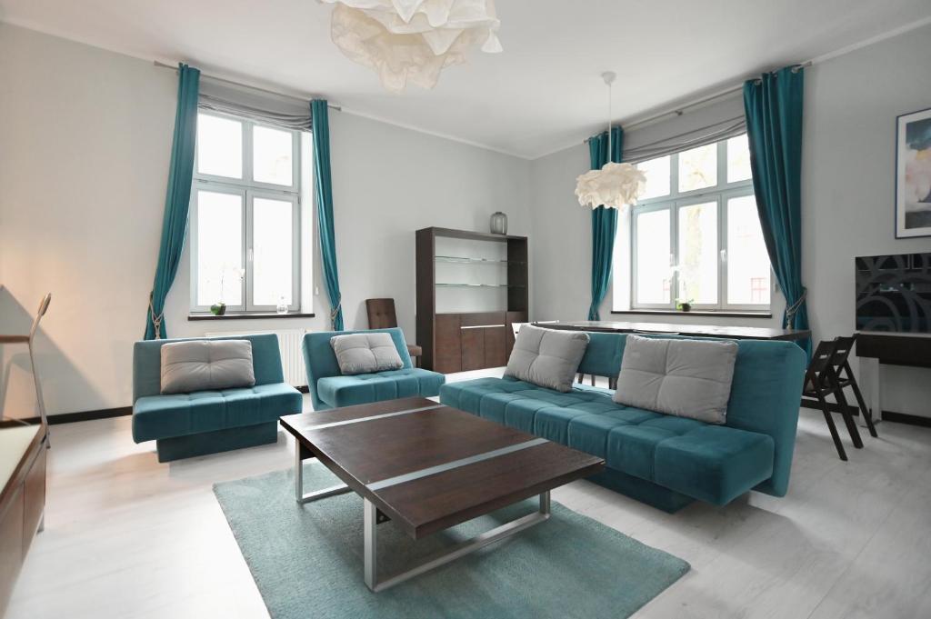 a living room with blue couches and a coffee table at Victus Apartamenty, Apartament Niebieski in Sopot