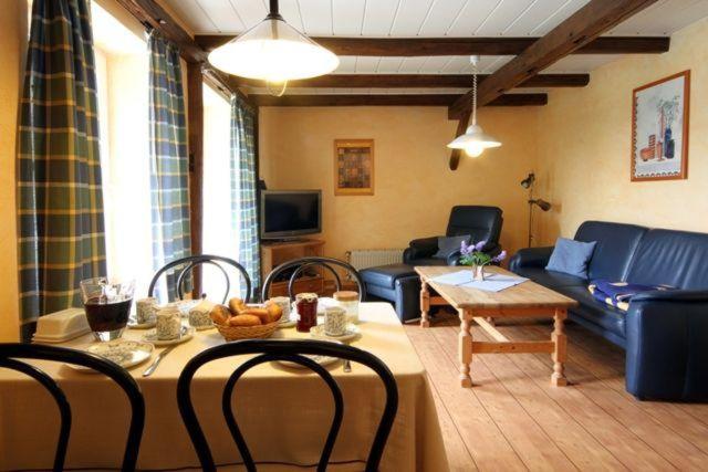 un soggiorno con un tavolo e un divano blu di Feriewohnung-Schrotkammer a Klausdorf