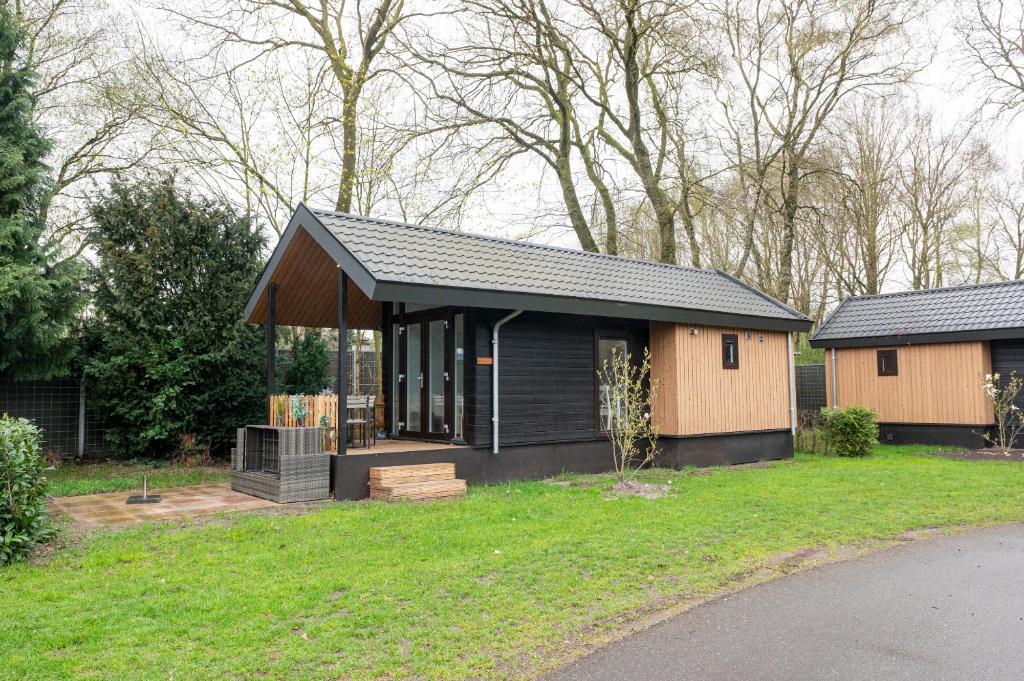 una pequeña casa con un techo negro en un patio en Camping de Konijnenberg Tiny House en Harderwijk
