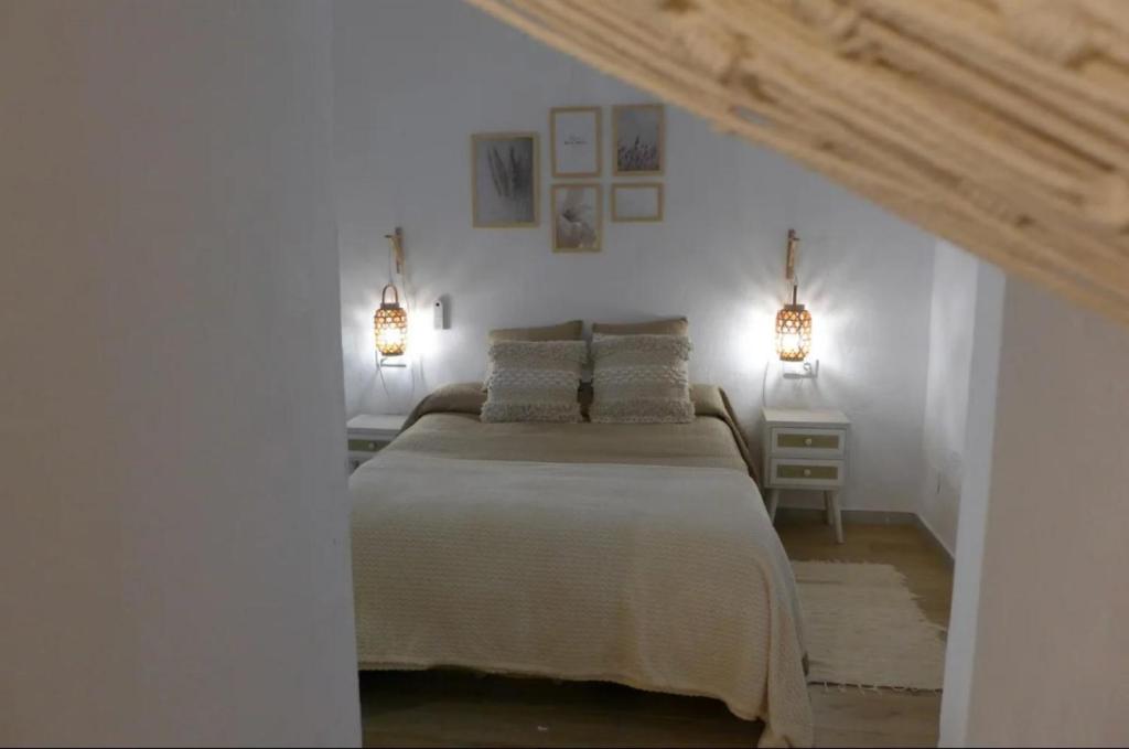 a white bedroom with a bed and two lights at Precioso loft en pleno centro histórico de Vejer in Vejer de la Frontera