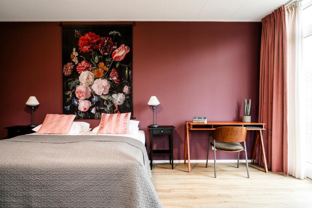 een slaapkamer met een schilderij van bloemen aan de muur bij de Logerie in Enkhuizen
