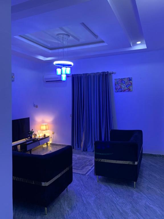 a living room with two couches and a blue light at Stobi Apartment in Abuja
