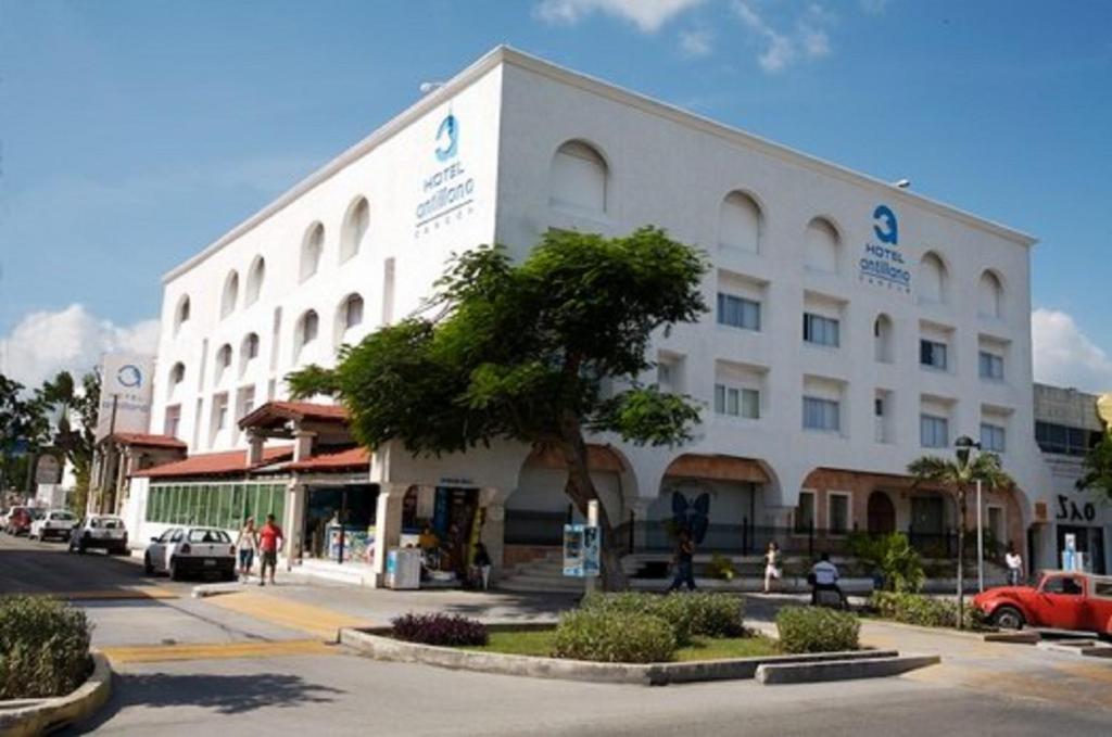 un gran edificio blanco con un árbol delante en Hotel Antillano, en Cancún