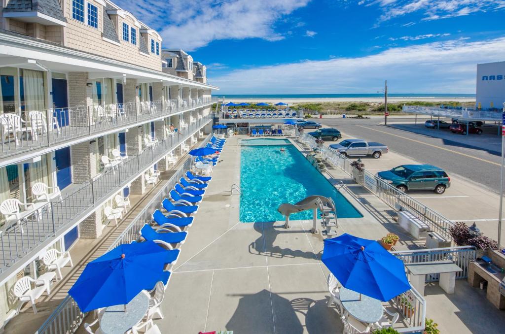 uma imagem de uma piscina num hotel com guarda-sóis azuis em Fleur de Lis Beach Motel em Wildwood Crest