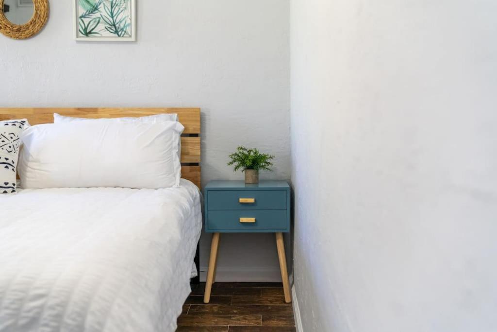 a bed with a blue nightstand with a plant on it at Hidden Gem Off Atlantic Ave, Just Steps From Beach in Delray Beach