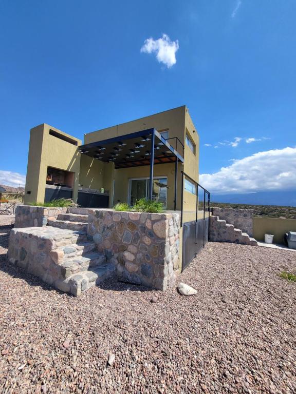 ein Haus in der Wüste mit einer Steinmauer in der Unterkunft Villamagna, casa en Potrerillos in Potrerillos