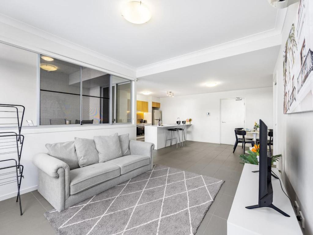 a living room with a couch and a kitchen at Chic Modern Retreat 1BR Apt w pool Kelvin Grove in Brisbane