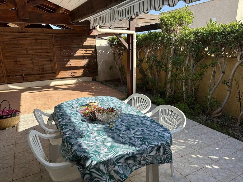 - une table avec des chaises blanches et une table avec des fleurs dans l'établissement HOLIDAYLAND 302 VILLA T3 MEZZANINE 8 couchages climatisé NARBONNE PLAGE, à Narbonne-Plage