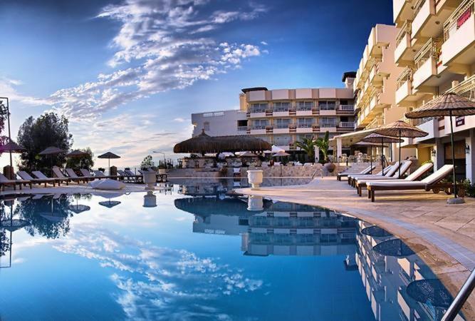 una piscina con sillas y sombrillas junto a un hotel en Hotel Carina, en Kusadasi