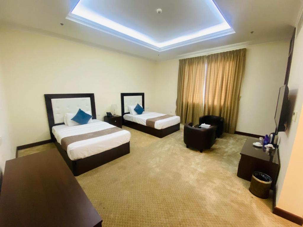 a hotel room with two beds and a television at A Line Hotel in Doha