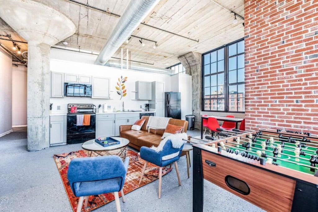 a living room with a ping pong table and a brick wall at STUNNING Architect loft by CozySuites in Saint Louis