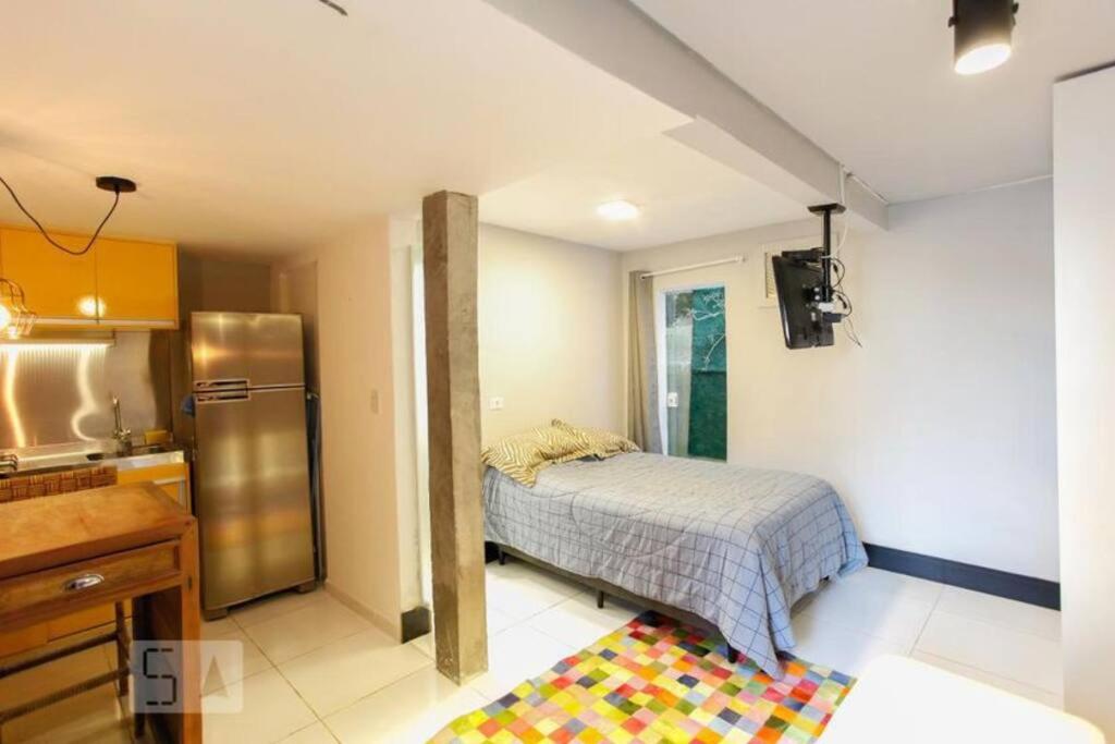 a bedroom with a bed and a kitchen with a refrigerator at Studio no Jabaquara a 2,8km da Expo imigrantes in Sao Paulo