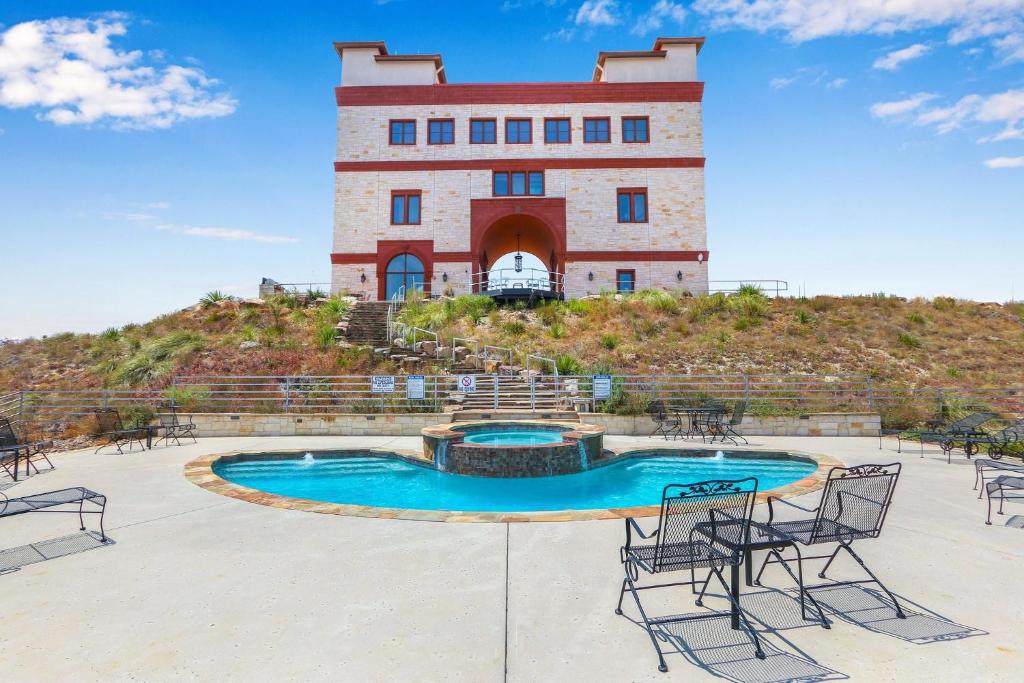 un edificio con piscina y sillas frente a él en Arc de Texas -Louis XIV Suite en Johnson City