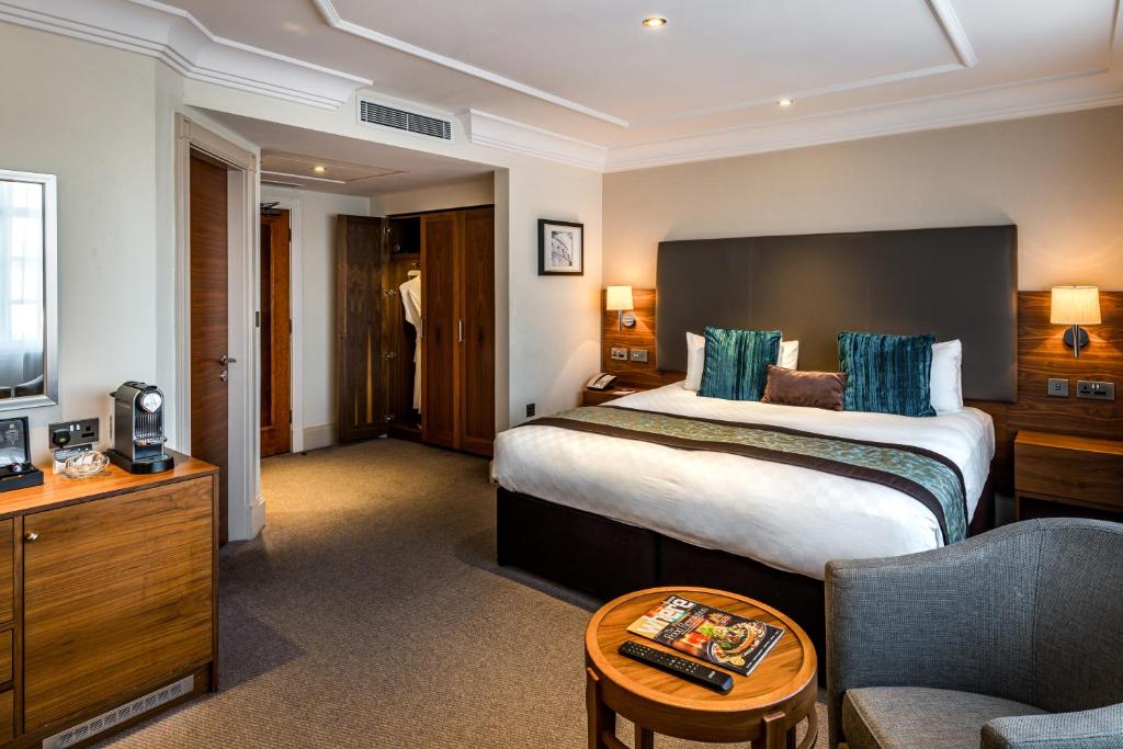 Thistle London Marble Arch في لندن: غرفة فندقية بسرير كبير واريكة