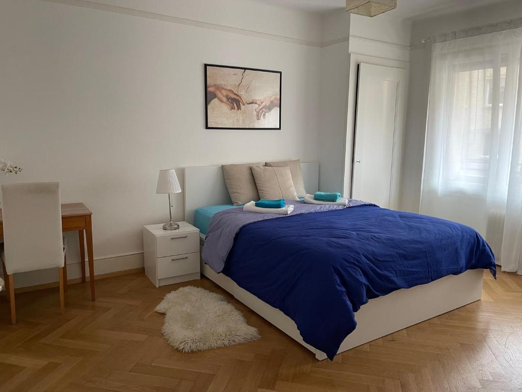 1 dormitorio con 1 cama grande con manta azul en Jolie chambre au centre ville, en Lausana