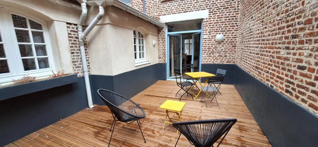 een patio met stoelen en tafels en een bakstenen muur bij "La cour du Noble" Hypercentre cour privative in Arras