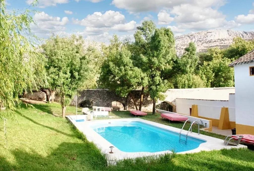 un patio trasero con una piscina en el césped en 6 bedrooms villa with private pool enclosed garden and wifi at Villanueva del Trabuco en Villanueva del Trabuco