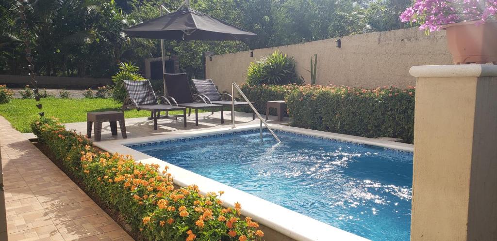 a swimming pool with chairs and an umbrella in a yard at Jarabacoa Villa Anchorage in Jarabacoa