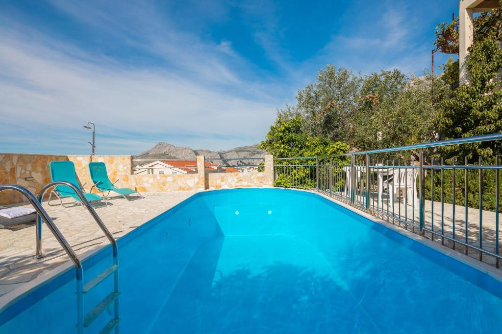 ein blauer Pool mit zwei Stühlen und einem Zaun in der Unterkunft XXL Apartment - Private Pool in Omiš