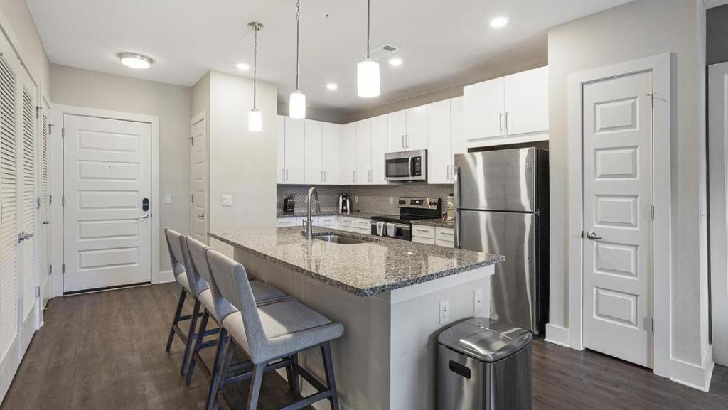 a kitchen with white cabinets and a stainless steel refrigerator at Landing at eXchange - 2 Bedrooms in Downtown Detroit in Detroit