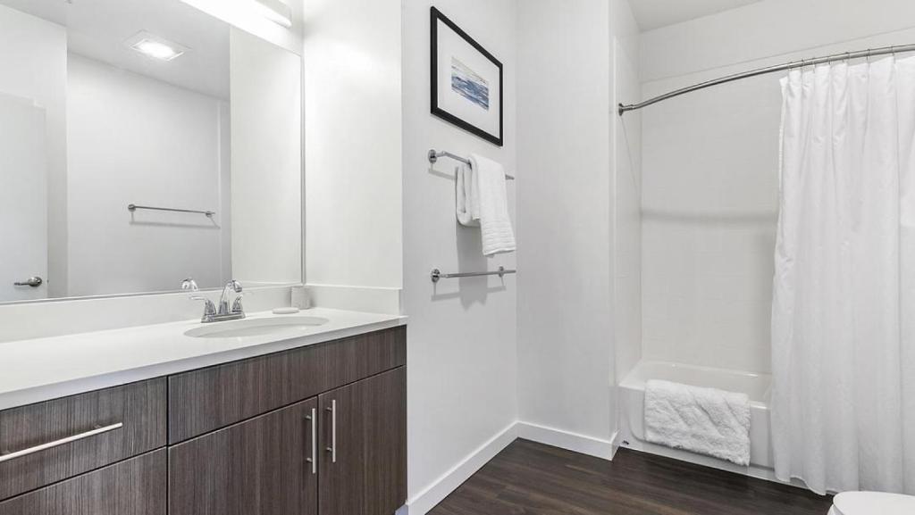 uma casa de banho branca com um lavatório e um espelho em Landing at eXchange - Studio in Downtown Detroit em Detroit