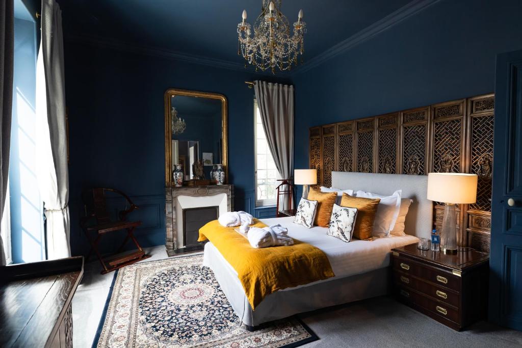Schlafzimmer mit blauen Wänden und einem Bett mit gelber Bettwäsche in der Unterkunft Domaine du Chesney in Pressagny l'Orgueilleux
