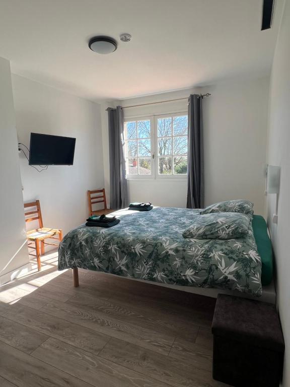 una camera da letto con un letto con un piumone verde e una finestra di Hôtel Restaurant La Tonnelle a Mios