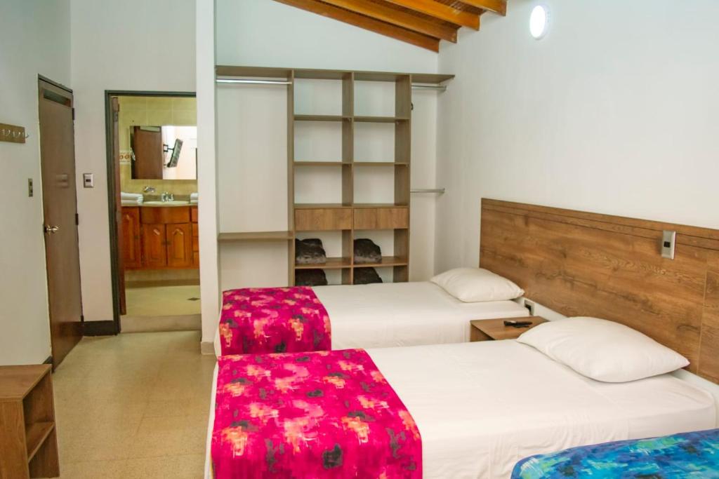 a bedroom with two beds and a red seat at Hotel Boutique Estadio in Medellín