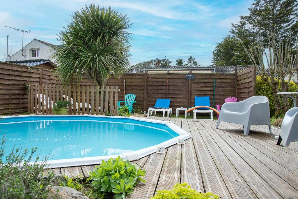 une cour arrière avec une piscine et des chaises et une terrasse en bois dans l'établissement New - Gite Angelina piscine et spa, à Saint-Jean-de-Monts