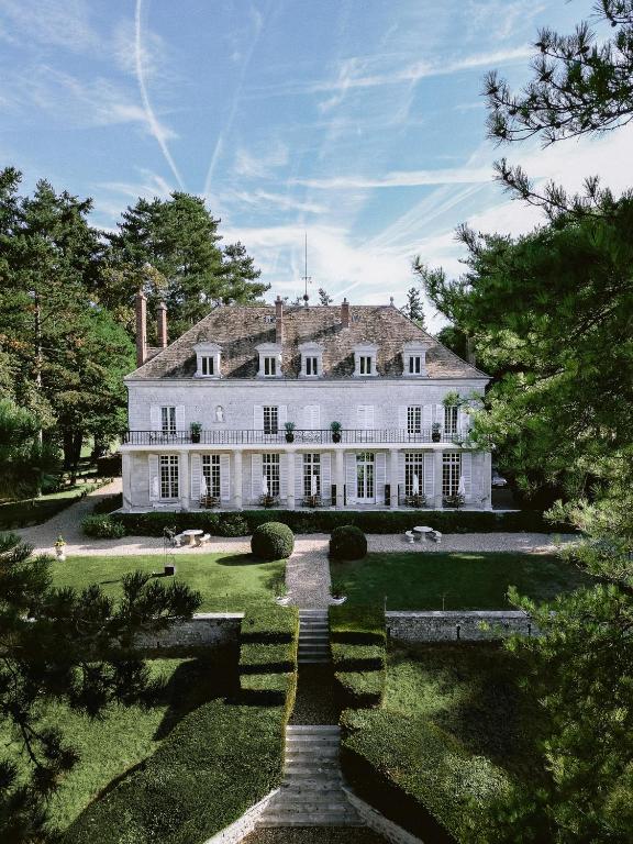 une grande maison blanche avec un jardin et des arbres dans l'établissement Domaine du Chesney, à Pressagny l'Orgueilleux