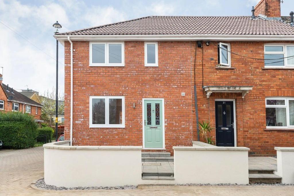 a brick house with a green door on a street at Dings Village Corner House by StayStaycations in Bristol